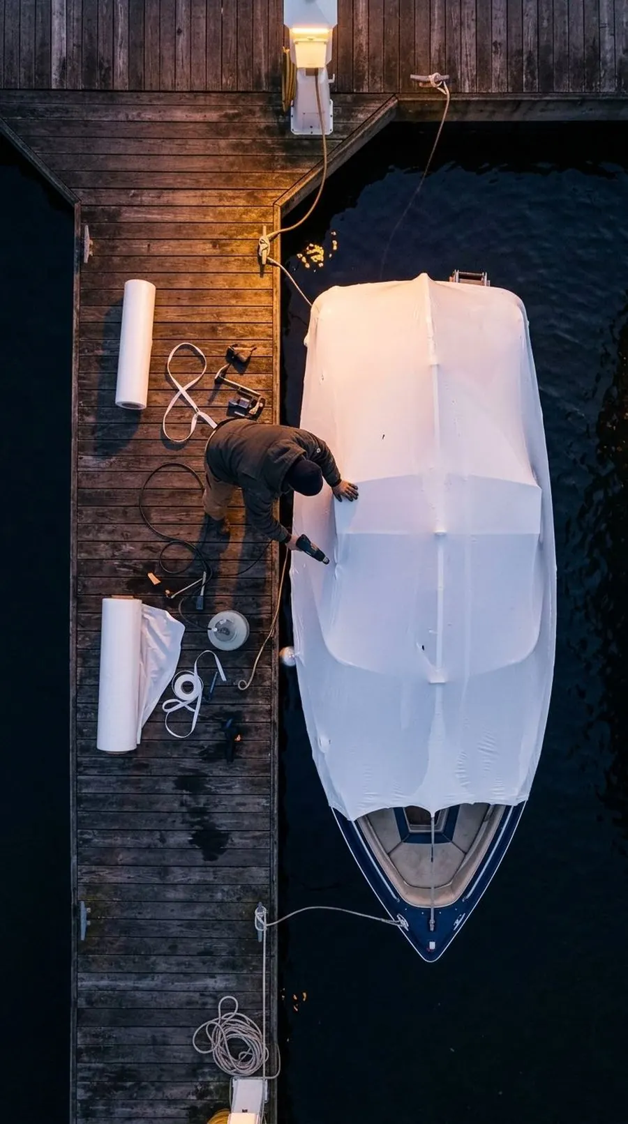 A crew shrink-wrapping a boat, seen from above
